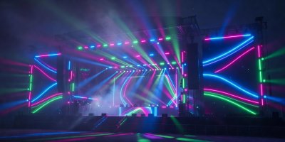 Glowing neon festival stage lights shining brightly through a soft atmospheric haze